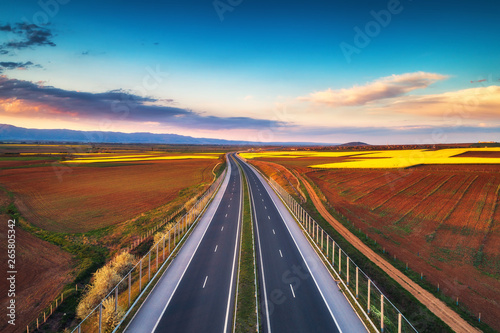 Aerial view of highway on sunset. Transportation background. Landscape with road near countryside fields