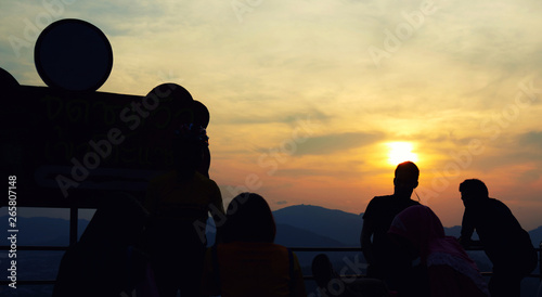 Silhouettes of group friends relaxing to looking at the sunrise or sunset enjoying perfect view. Holiday and vacation concept. photo
