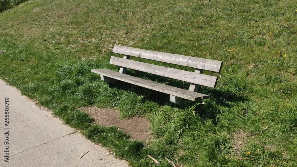 Wooden park bench near a sidewalk Wooden park bench near a sidewalk
