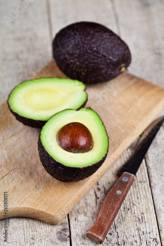 Avocado and knife on cutting board on old wooden table background.
