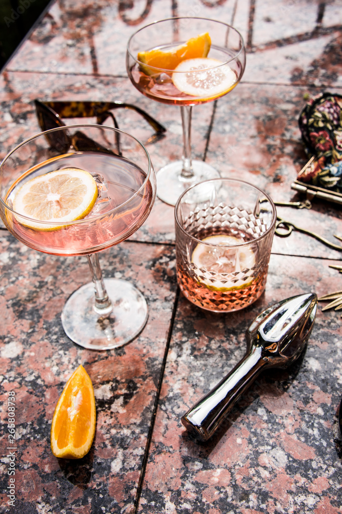 Naklejka premium Rose wine in wineglasses. Wine tasting, garden party and celebration in the summer. Still life and lifestyle in the garden with artistic shadows.