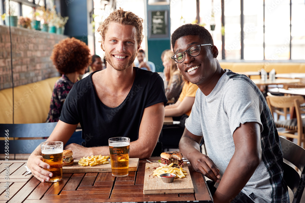 Portrait Of Two Young Male Friends Meeting For Drinks In Restaurant