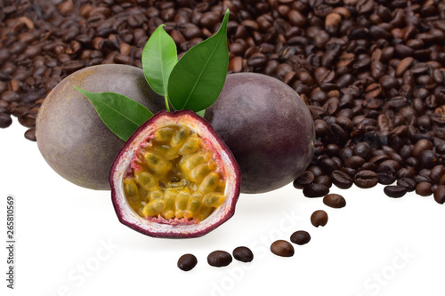 Two passion fruits, half with ripe juicy seeds and green young leaves against the background of fragrant roasted coffee beans