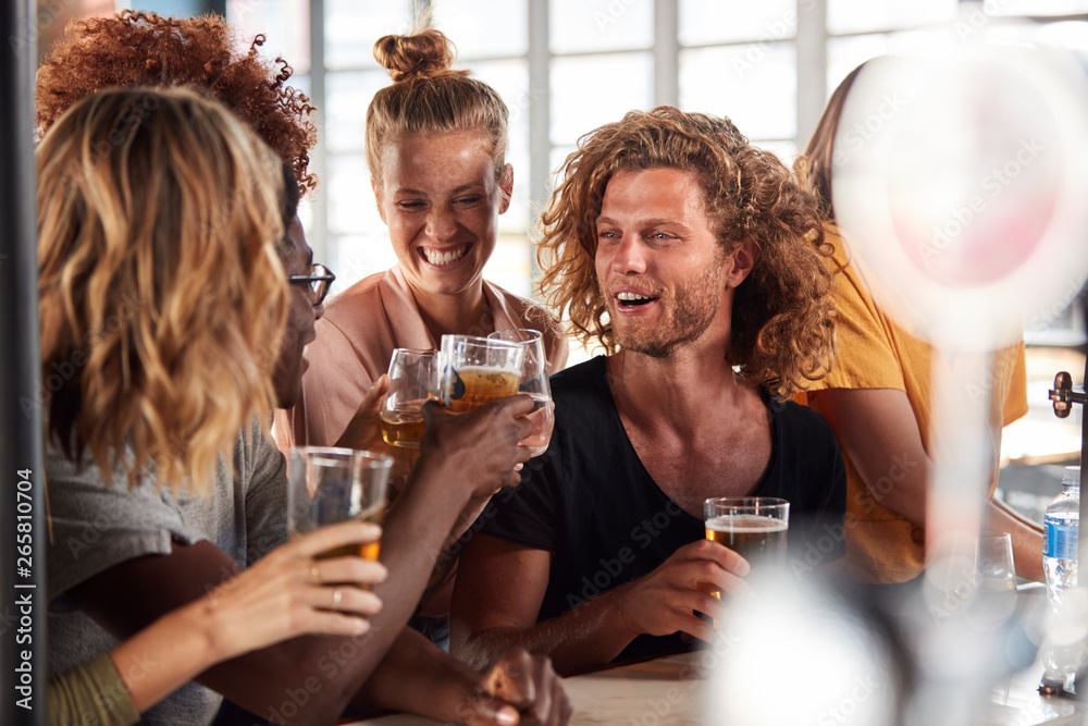 Group Of Male And Female Friends Celebrating Whilst Watching Game On Screen In Sports Bar Group Of Male And Female Friends Celebrating Whilst Watching Game On Screen In Sports Bar