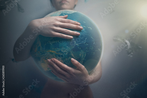 Fototapeta Naklejka Na Ścianę i Meble -  Woman embracing the globe of planet Earth. The concept of preserving the environment and love for your planet. Tint and loght. Dark colors