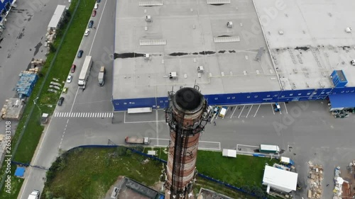 Summer cityscape under cloudy sky. View of plant pipe chimney smoke in the industrial part of city surroundings.