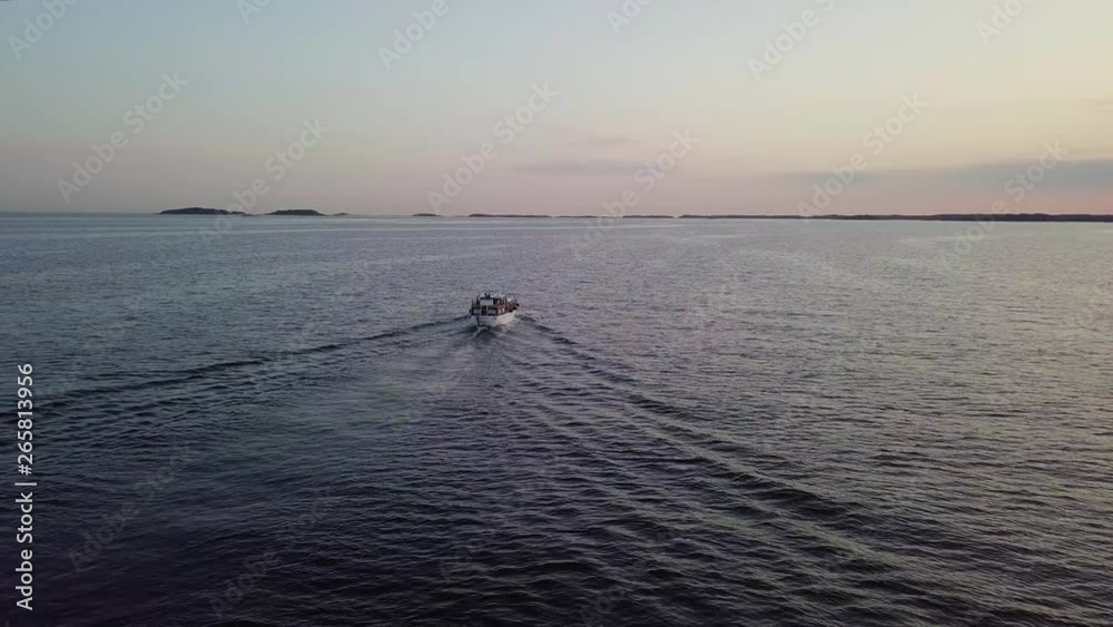 A FAST CIRCLING AERIAL VIEW of a boat travelling on the sea at sunset. DOLLY SHOT. A FAST CIRCLING AERIAL VIEW of a boat travelling on the sea at sunset. DOLLY SHOT.