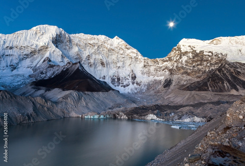 Gray moraine lake and snowy mountain peak in the moonlight in Himalayas, Nepal. Decent photo. photo