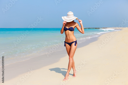 Sexy beautiful tanned woman relaxing and sunbathing in bikini on sea background and palm. Panoramic view from Jumeirah beach Dubai, UAE. Famous tourist destination.