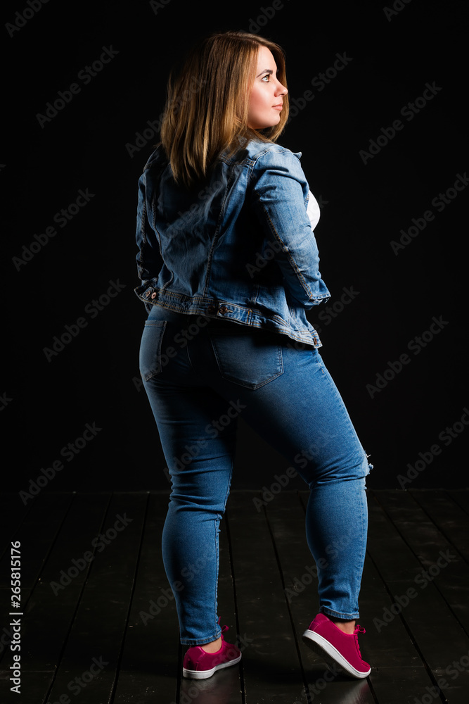 Plus size fashion model in blue jeans, fat woman on black studio  background, overweight female body foto de Stock | Adobe Stock