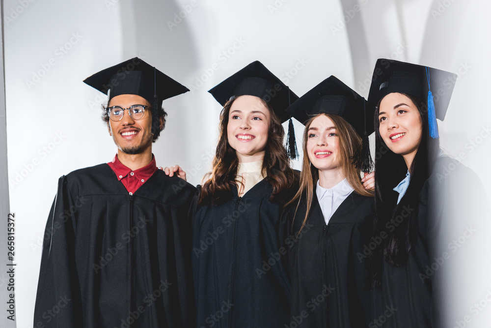 group of cheerful students in graduation caps smiling in university