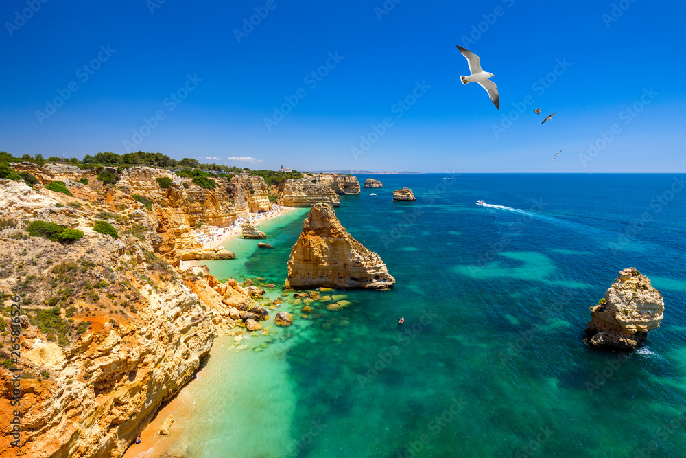 Praia da Marinha, beautiful beach Marinha in Algarve, Portugal. Navy Beach (Praia da Marinha) with flying seagulls over the beach, located on the Atlantic coast in Lagoa Municipality, Algarve. Praia da Marinha, beautiful beach Marinha in Algarve, Portugal. Navy Beach (Praia da Marinha) with flying seagulls over the beach, located on the Atlantic coast in Lagoa Municipality, Algarve.