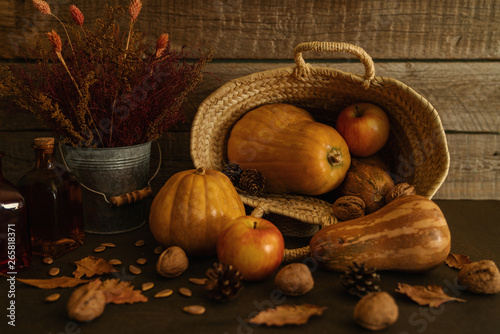 Colored fall vegenables on the vintage boards. Autumn decorations in wicker basket. A cornucopia with squash, gourds, pumpkins, cones, wheat and leaves. Toned image with copy space. Harvest time. photo