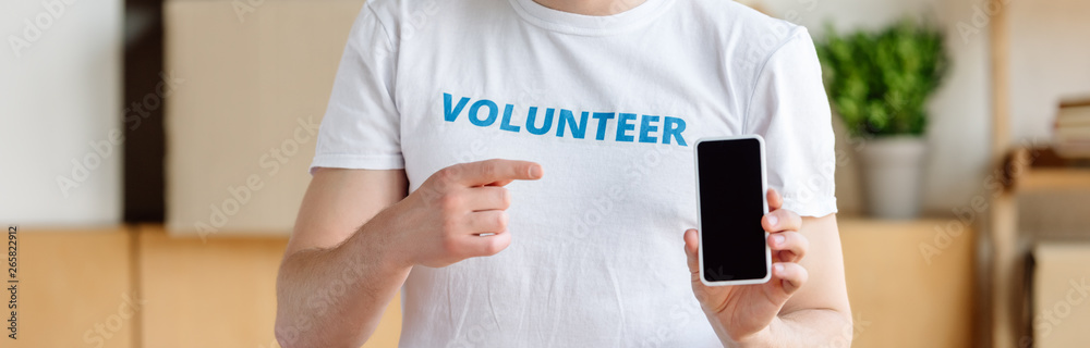 panoramic shot of volunteer showing with finger at smartphone with blank screen panoramic shot of volunteer showing with finger at smartphone with blank screen