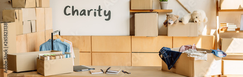 panoramic shot of cardboard boxes with books and clothes, wooden cabinets and placard with charity inscription © LIGHTFIELD STUDIOS