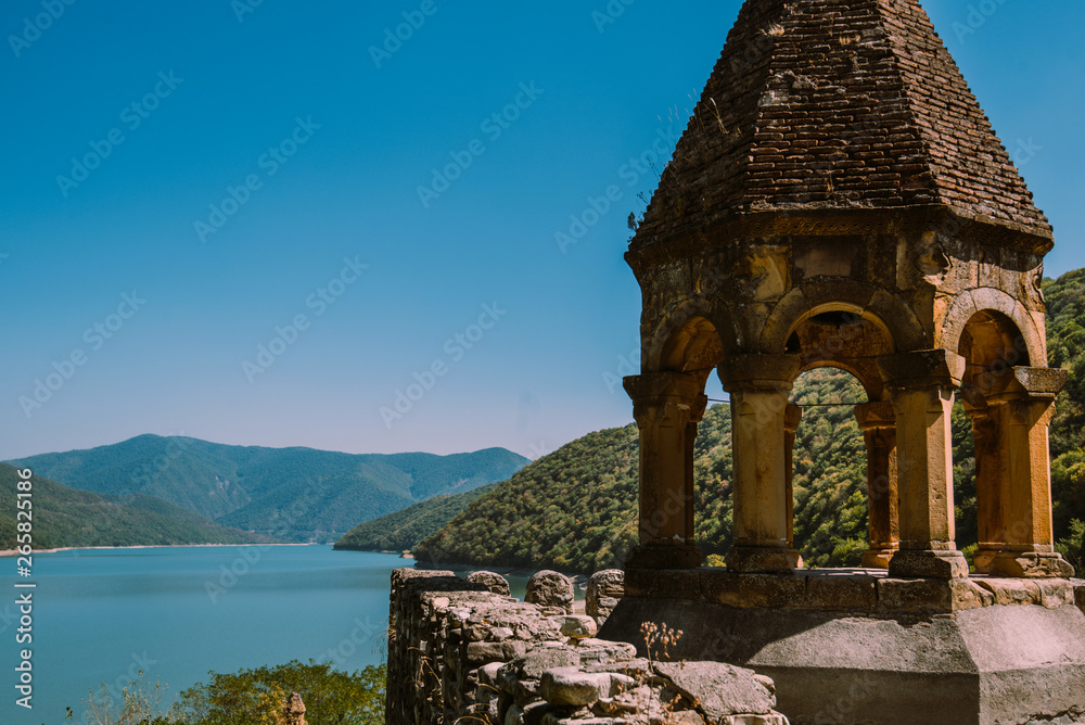 Obraz premium Ananuri castle complex on the Aragvi river in Georgia. Turquoise water surface and forest mountains. Medieval complex: castle and church against azure lake and mountains landscape background.