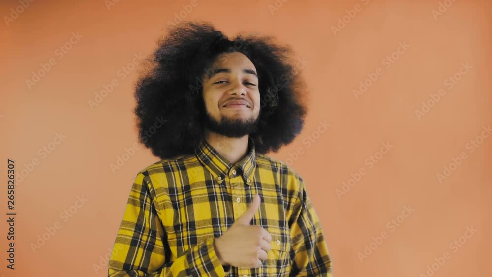 Young happy afro american man smiling while giving thumbs up on Orange background. Concept of emotions Young happy afro american man smiling while giving thumbs up on Orange background. Concept of emotions