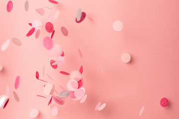 Pink confetti on pink background. Copyspace for text. Bright and festive holiday background.