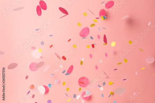 Colorful confetti on pastel pink background. Bright and festive holiday background.