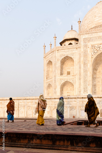 Vier Frauen in Gewändern laufen vor dem Taj Mahal im Sonnenaufgang 
