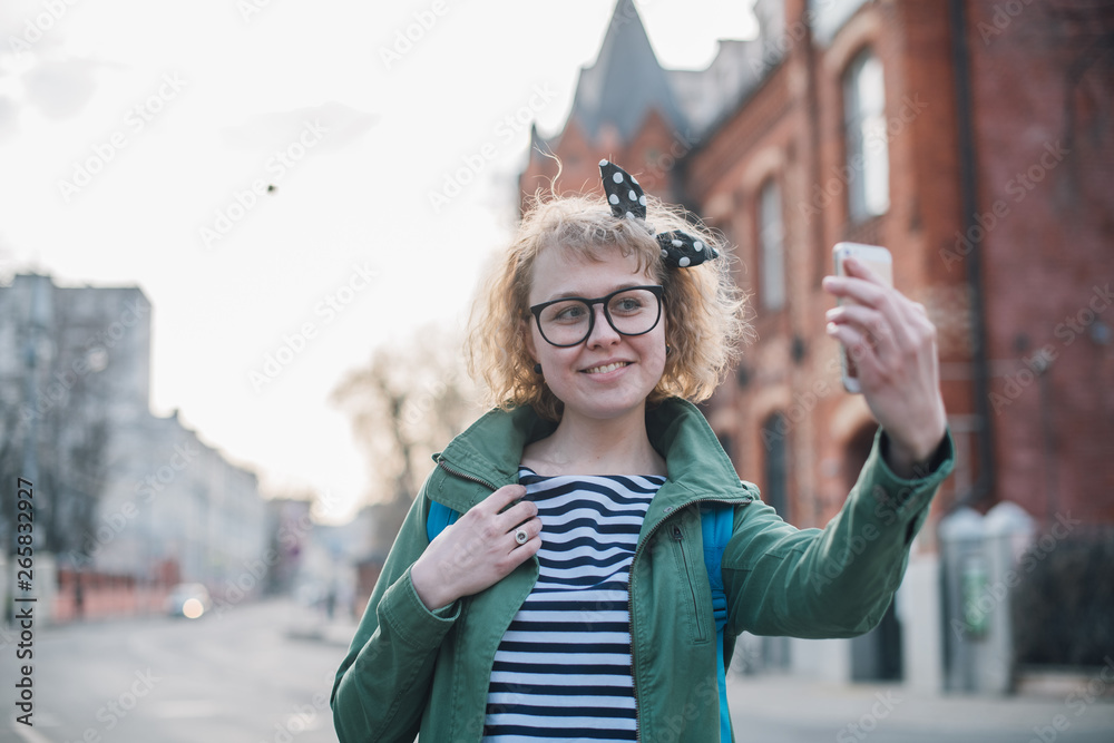 Young woman making selfie on the background of the European sunny street. Young woman making selfie on the background of the European sunny street.
