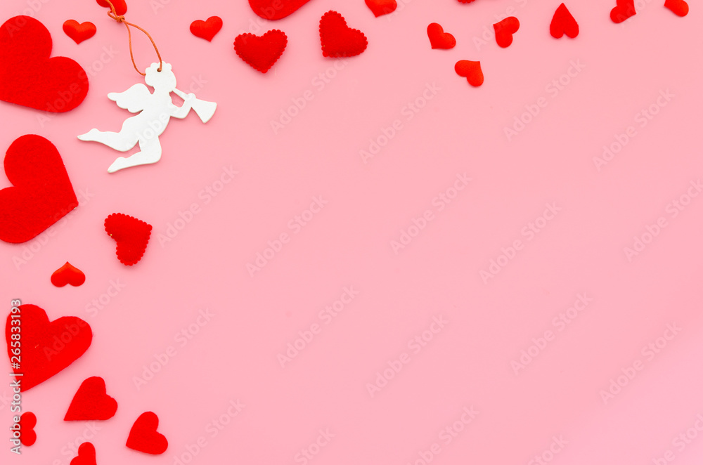 Flat lay red felt hearts with cupid angel on a pink background. Corner arrangement with copy space. Happy Valentines day concept