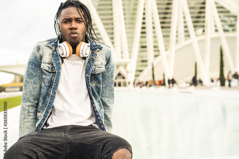 Outdoor portrait of a handsome and attractive young African american man with music headphones on the street