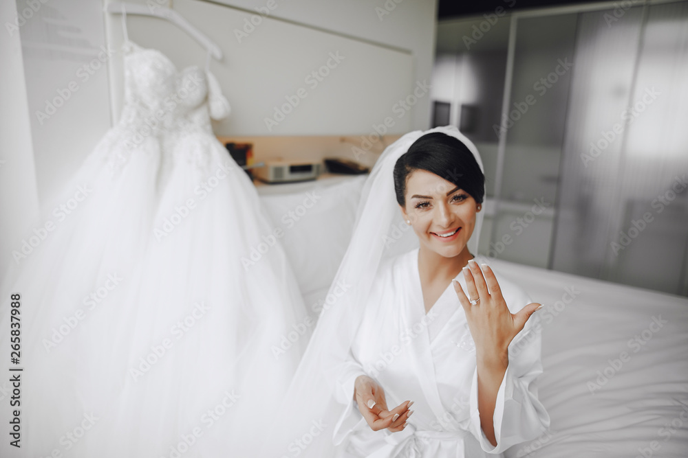 A elegant and beautiful bride at home sitting in a bed near window A elegant and beautiful bride at home sitting in a bed near window