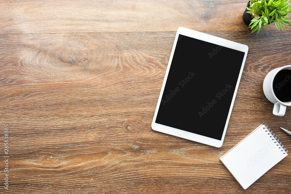 White tablet with black blank screen is on top of wood desk table with supplies. Top view with copy space, flat lay. White tablet with black blank screen is on top of wood desk table with supplies. Top view with copy space, flat lay.