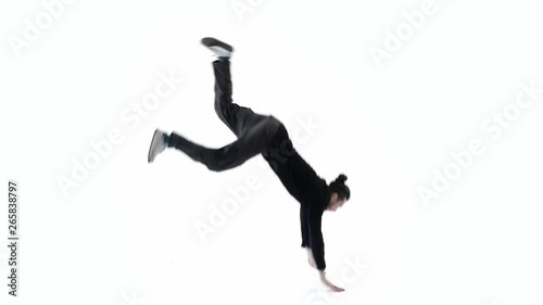 A man dancer jumps overturns and stands on the floor in an unusual position with his legs up.Black clothes on a white background.Slow motion (ID: 265838797)