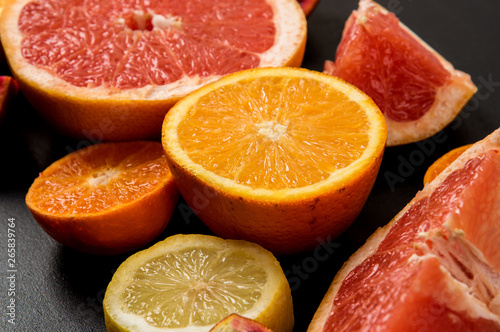 Close up. Colorful slices juicy grapefruits  oranges on a black background. Ingredients.