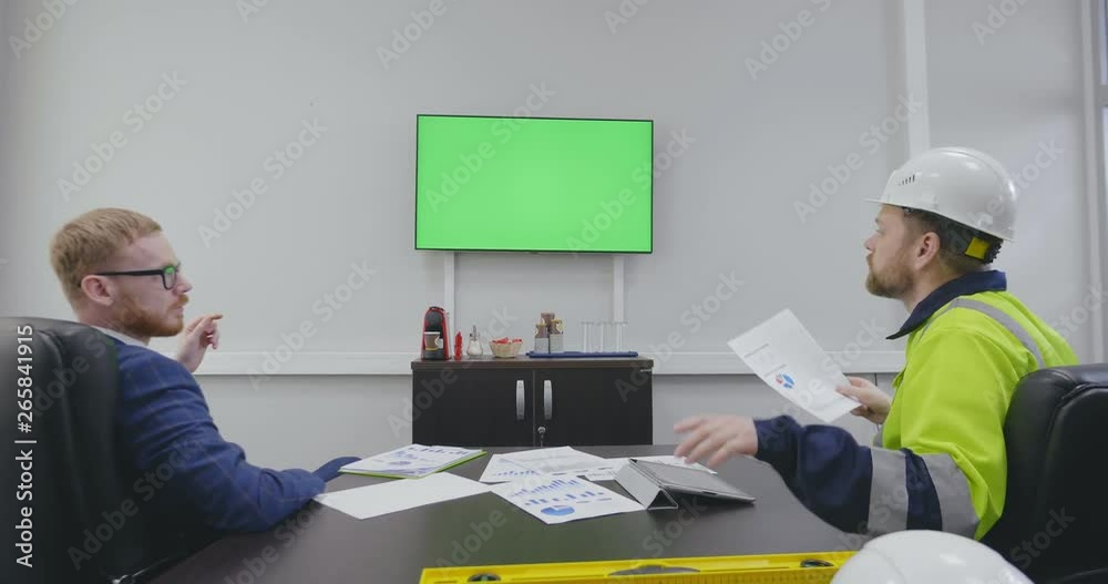 engineer and director discuss project in office.