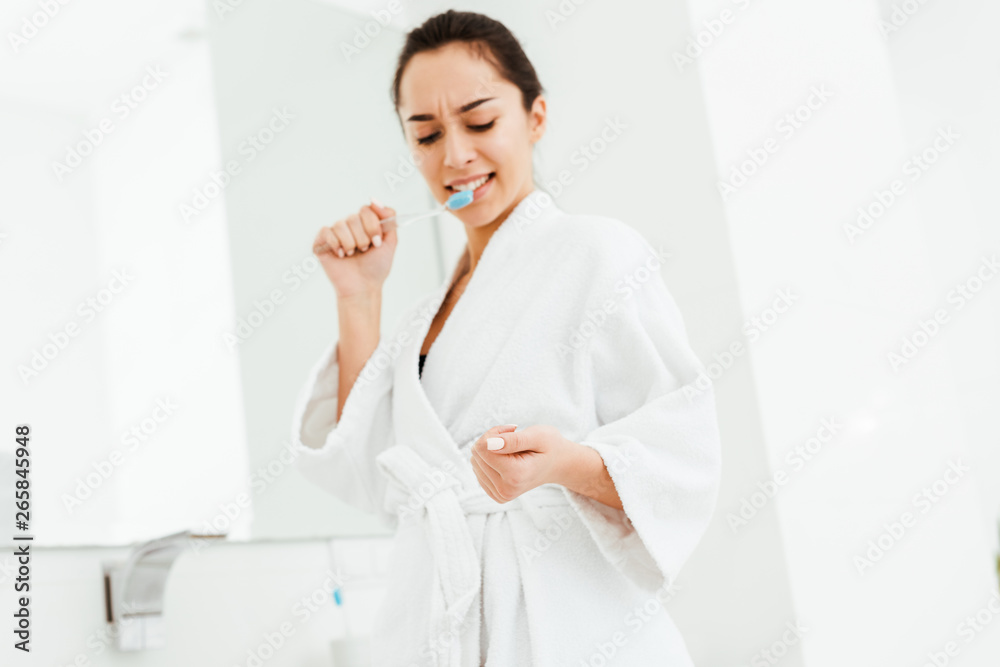 low angle view of attractive woman holding toothbrush and looking at hand low angle view of attractive woman holding toothbrush and looking at hand