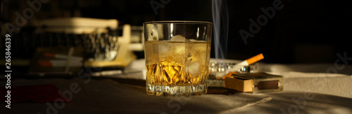 Panorama still life with a glass of whiskey, a cigarette and a typewriter in retro style