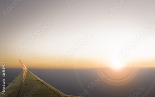 Sunset  cloudy sky and airplane wing as seen through window of an aircraft