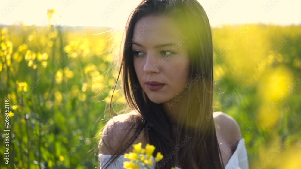 Mysterious girl posing among field of canola Mysterious girl posing among field of canola