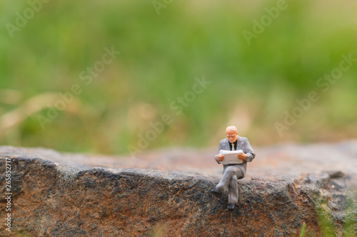 Miniature people: Business man reading newspaper with copy space