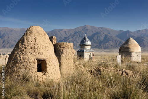 Foto Mud brick mausoleum in cemetery at Altyn Emel Park with Koyandy Ak Tau mountain