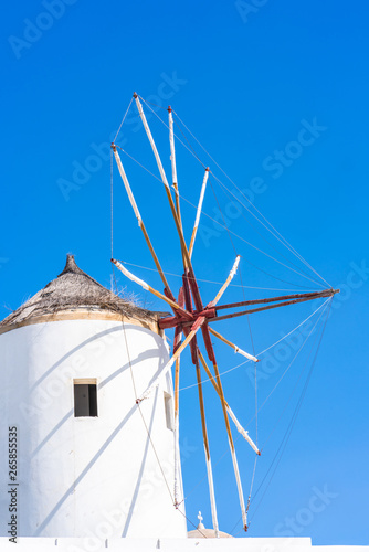 Traditional white windmill against blue sky in Oia on Cyclades island of Santorini, Greece