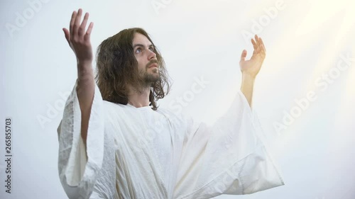 Saint man in robe raising hands to light, praying to God, religious conversion photo