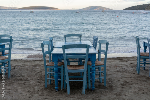 Traditional greek tavern with wooden tables on sandy beach near water waiting for tourists in Tolo  Peloponnese  Greece