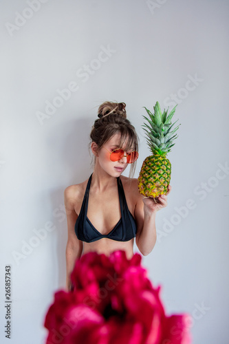 Adult woman in bikini with pineapple and sunglases
