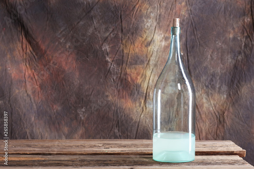 The bottle and glass of moonshine on the old wooden table photo