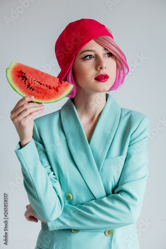 portrait of a young girl with pink hair in formal clothes of the 80s with a slice of watermelon