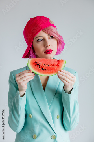 portrait of a young girl with pink hair in formal clothes of the 80s with a slice of watermelon