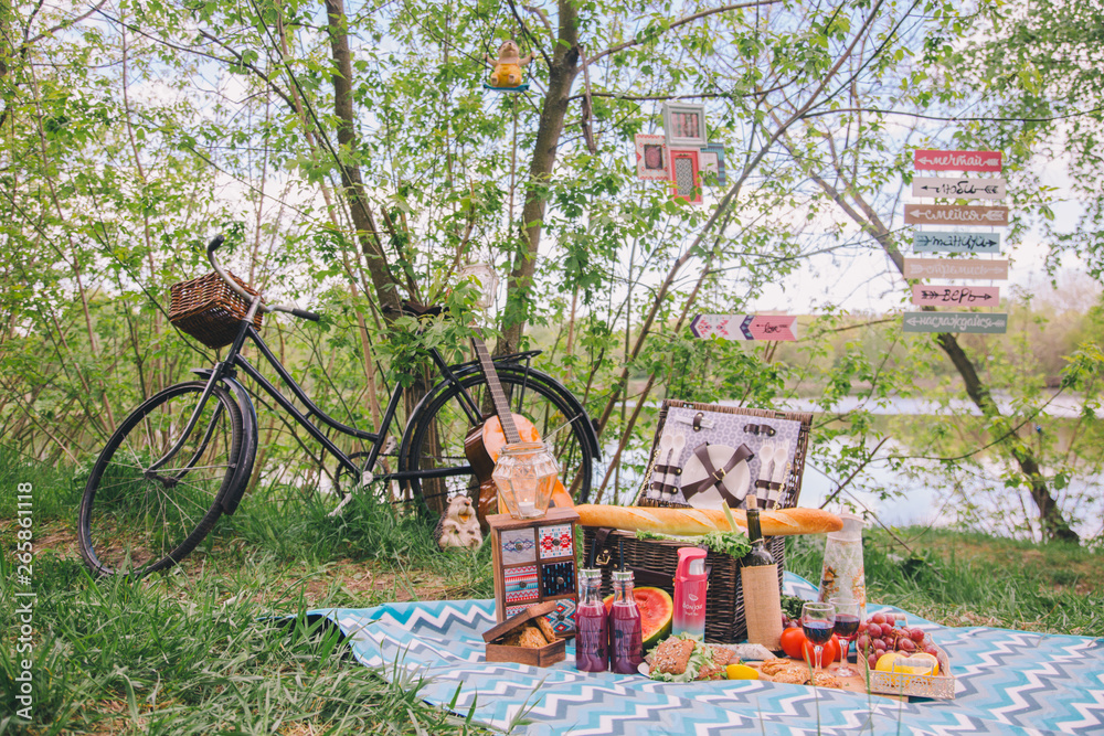 Design summer picnic in nature. On the plaid is a basket of food. On the background of a bicycle and decorative ornaments