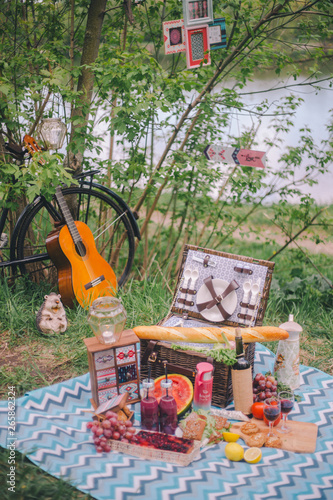 Design summer picnic in nature. On the plaid is a basket of food. On the background of a bicycle and decorative ornaments
