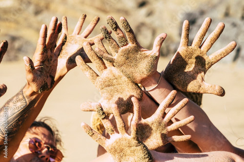 Friendship anmd happiness and joyful concept with group of young happy people showing and playing with hands dirty of sand at the beach during summer joy holiday vacation outdoor photo