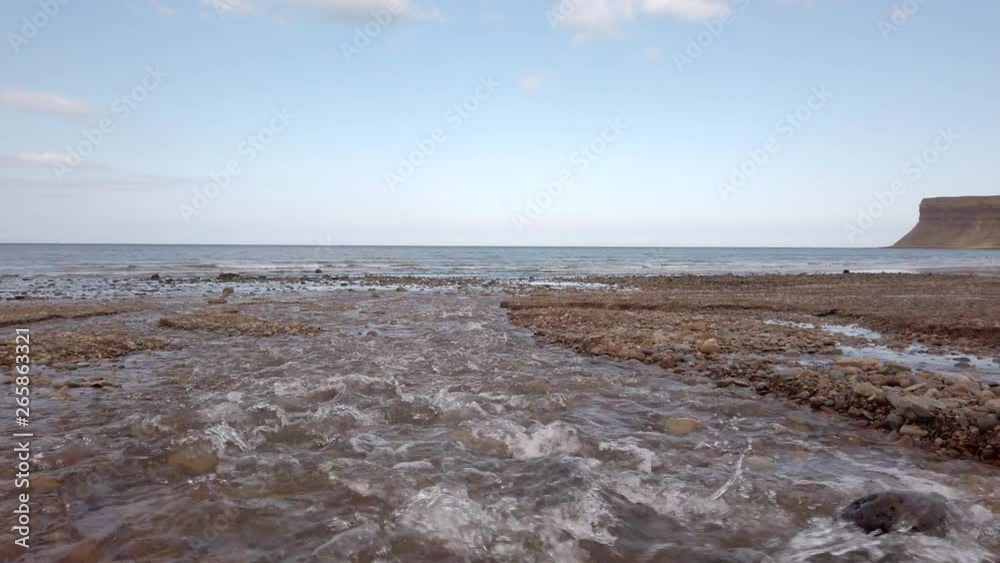 Slow Motion Left Pan of Stream Rushing into the Ocean at the Beach Slow Motion Left Pan of Stream Rushing into the Ocean at the Beach