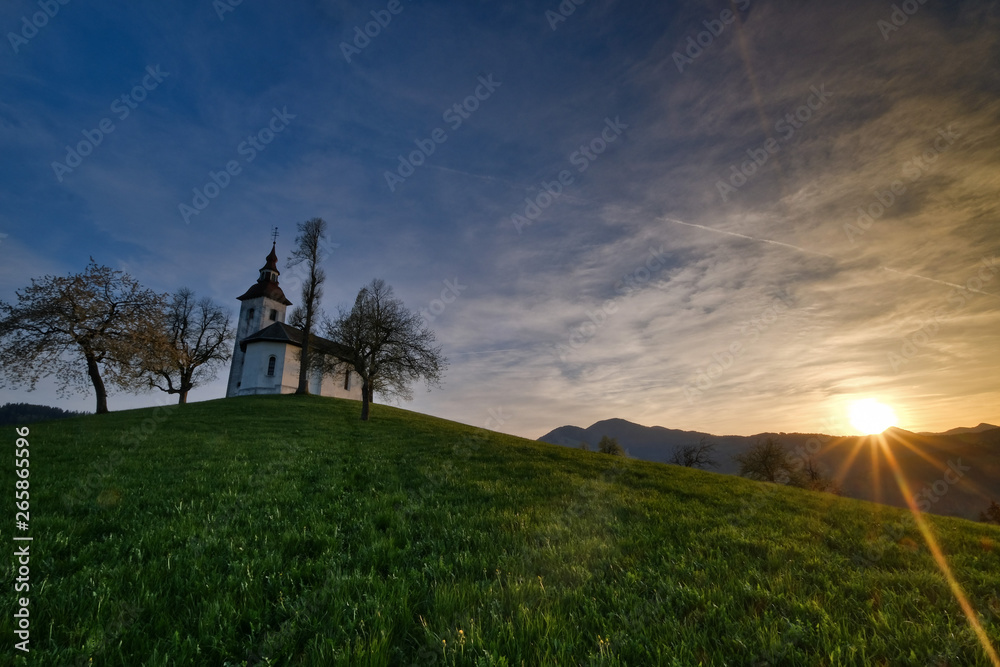 St.Tomas church near Skofja Loka in sunest with spring grass